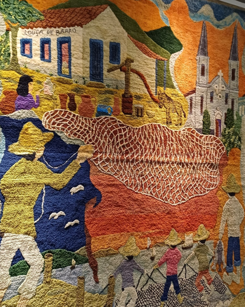 Detalhe do painel da direita com a casa “Louça de Barro”, uma mulher ao lado de potes de cerâmica, um poço com bomba e um burro, e à frente o pescador lançando a tarrafa, com gaivotas brancas ao fundo e pescadores de chapéu de palha na praia.