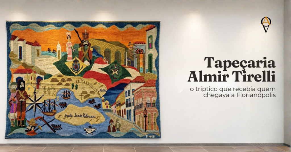 Capa do artigo com o título “Tapeçaria Almir Tirelli” e o subtítulo “o tríptico que recebia quem chegava a Florianópolis” à direita, em letras escuras sobre fundo branco, e o logotipo do Onde Ver Arte no canto superior direito. À esquerda, o painel central da tapeçaria Almir Tirelli está pendurado numa parede branca iluminada por focos de luz, com borda azul ondulada e a assinatura “Tirelli” no canto inferior direito. A lã colorida mostra um mapa antigo da Ilha de Santa Catarina em tons de areia e azul, com inscrição em latim, rosa dos ventos, caravelas e barcos a remo. Em volta do mapa aparecem um casal ao fundo, ao lado de um soldado de lança, brasões e bandeiras nas cores verde, vermelha e branca, arcadas de pedra sob um céu laranja e, à direita, sobrados antigos com sacadas e um poste de luz numa rua de pedras.